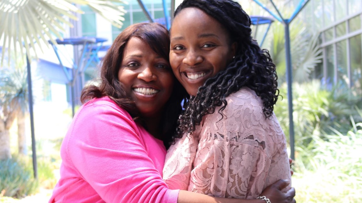 Black female nurse Tammy Turner hugging daughter in the healing garden