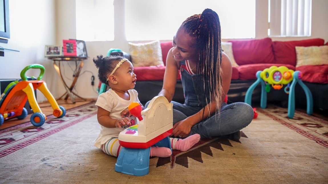 Young black mother sitting on the floor playing with baby