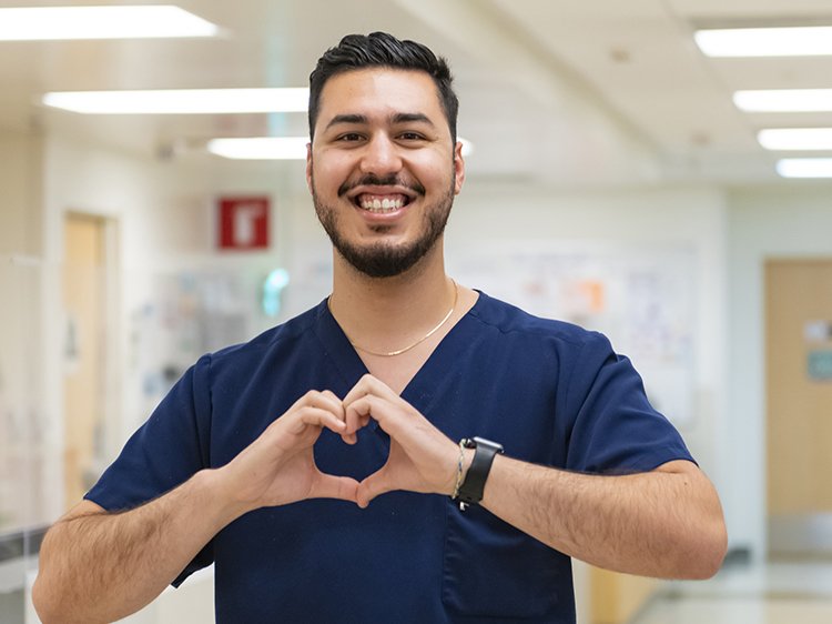 Fotografía de un enfermero sonriendo y haciendo un corazón con las manos